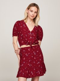 Röd blommig kortärmad crop top med puffärmar och V-ringning, knuten i midjan. Matchande utsvängd mini kjol med blommönster.