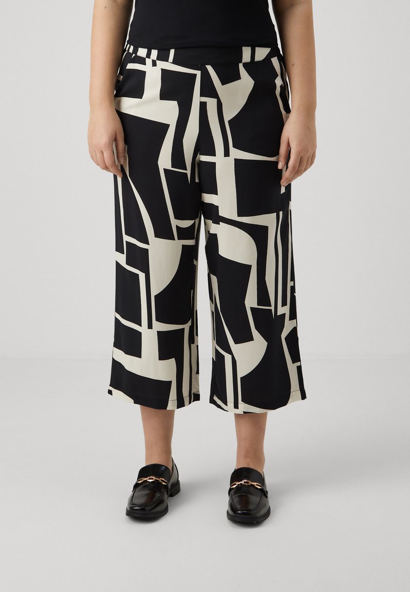 Pantalons large à motifs noir et blanc avec des formes géométriques, en tissu léger. Devant plat avec poches et coupe décontractée.