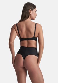 Schwarzes Bikini-Set mit einer hochgelegten Unterhose und verstellbaren Trägern. Glatter Stoff mit nahtlosem Design und minimalem Zubehör.