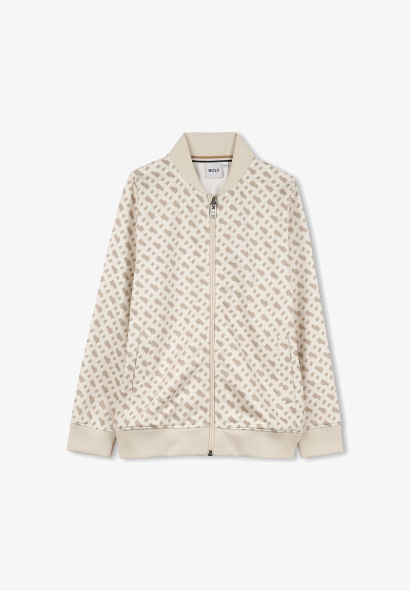 Veste zippée beige avec un motif géométrique beige, col et poignets côtelés, et poches latérales ; fabriquée à partir d'un tissu doux et texturé.