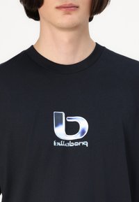 Juodas marškinėliai su atspindinčia logotipu, kuriame stilizuota raidė "b" ir tekstas "bullabq" po ja. Minkšta medžiaga su apvalia apykakle.