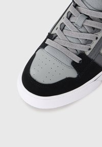 Čierne a šedé tenisky so hladkým koženým špičkou, sieťovinovou jazykovou časťou, zamakmi a bielou gumovou podrážkou s textúrovaným gripom.