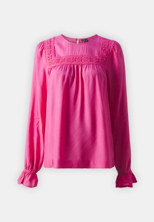 Blusa rosa de manga longa com detalhes em renda ao longo do decote, corpete franzido e punhos com babados, feita de tecido leve.