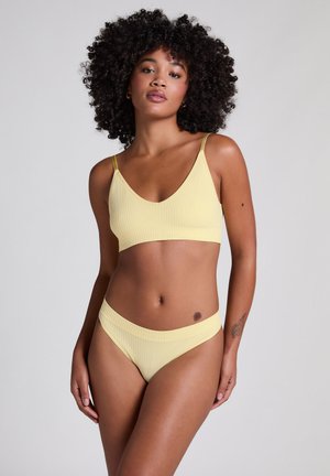 Bralette jaune à côtes et bas de bikini assorti, arborant des bretelles fines et un design sans coutures avec une texture douce et des détails minimaux.