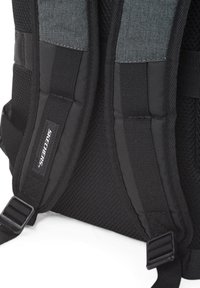Mochila negra y gris con correas de hombro acolchadas de malla y tela texturizada. Cuenta con hebillas ajustables y una etiqueta de marca en una de las correas.