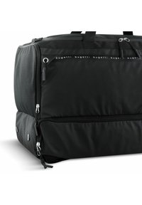 Sac de voyage en tissu noir avec plusieurs compartiments zippés, présentant une texture lisse, des poignées robustes et des accents en métal argenté.