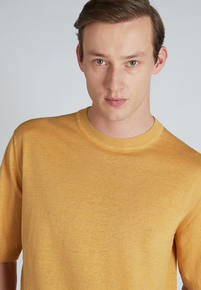 Maglione a maniche corte con scollo rotondo in un uniforme giallo senape, caratterizzato da una texture morbida e una silhouette aderente.