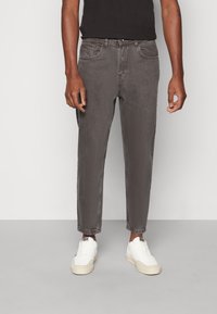 Szare dżinsy z denimu o luźnym kroju, prostych nogawkach, czterech kieszeniach i subtelnym spranym efekcie; zestawione z białymi trampkami.