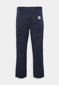 Donker marineblauwe werkbroek gemaakt van stevige stof, met twee achterzakken en een vierkant logo-embleem boven de rechterzak. Comfortabele pasvorm, rechte pijpen.