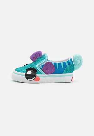 Chaussure enfant turquoise pailletée à enfiler avec des oreilles en tissu violettes, une queue duveteuse bleu sarcelle, des patchs noirs autour des yeux et un détail langue rouge sur une semelle blanche.