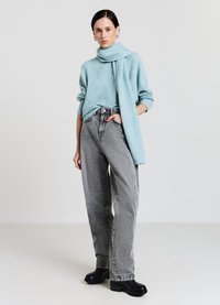 Maglione lavorato a maglia azzurro chiaro con una sciarpa abbinata, abbinato a jeans comodi a vita alta con motivo in bianco e nero e stivali con plateau neri.