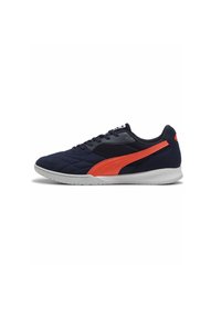 Zapatilla deportiva azul marino con parte superior texturizada, acentos naranjas y suela de goma blanca. Cuenta con un cuello acolchado y un sistema de cordones tradicional.