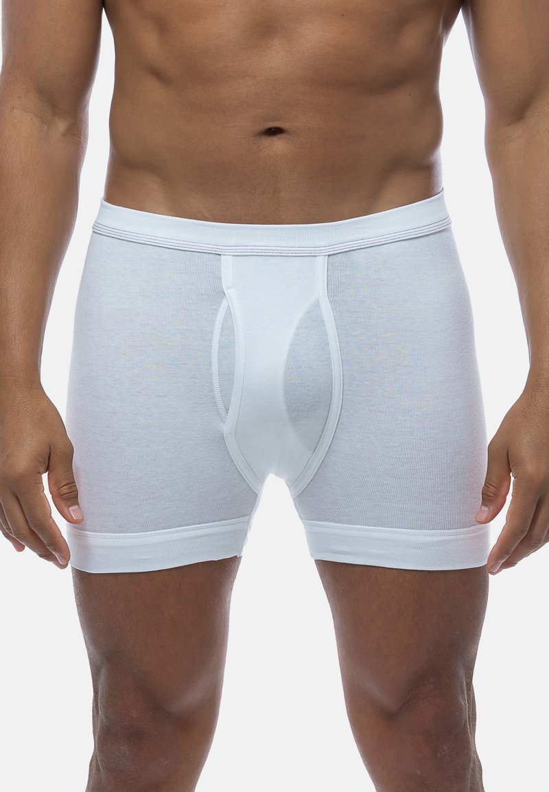 Boxer aderenti in cotone bianco con una texture a coste, dotati di una tasca sagomata, un elastico in vita e di un colore uniforme.