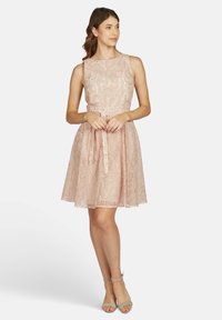 Schnürrkleid in zartem Rosa mit enganliegendem Oberteil, ausgestelltem Rock und gebundenem Taillenbereich. Verfügt über einen runden Ausschnitt und ärmelloses Design.