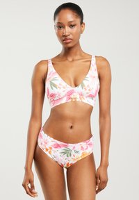 Kostium bikini w kwiaty z różowo-białym tłem i żywymi wzorami kwiatowymi. Góra ma dekolt w kształcie litery V, a dół ma średni stan.