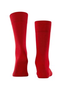 Medias rojas hasta la rodilla hechas de un material suave y elástico. Presentan una parte superior acanalada y una textura suave en toda su longitud, con una discreta marca en la punta.