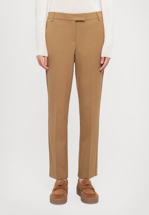 Brune skreddersydde bukser med rett snitt, frontlommer og skjult glidelås, parret med beige semsket skinn slip-on sko.