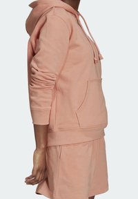 Rosa tyghoodie med en känguruficka, dragskohuva och ribbade muddar, i kombination med matchande shorts i en avslappnad passform.