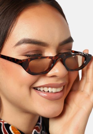 Lunettes de soleil en écaille de tortue avec un design étroit et angulaire et des verres teintés. Présentent des accents métalliques subtils sur les branches.