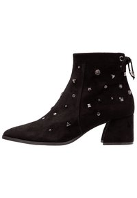 Stivaletto in pelle scamosciata nera con punta affusolata, tacco a blocco e decorazioni metalliche, tra cui stelle e forme geometriche.