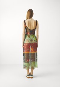 Transparent maxi dress featuring a colorful graphic print with intricate patterns. The design includes thin straps and a low back.