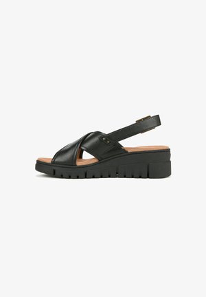 Black leather sandal featuring a crisscross design, cork footbed, and a chunky rubber sole with grooves for traction. Adjustable strap included.