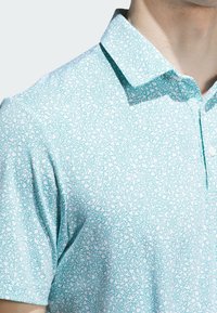 Short-sleeve shirt made of lightweight fabric, featuring a turquoise and white abstract pattern and a classic collar with button placket.
