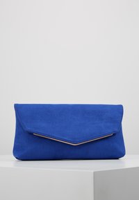 Blå mockaväska med triangelformat lock och guldfärgad detalj längs öppningen. Slät textur och mjuk finish. Rektangulär form.