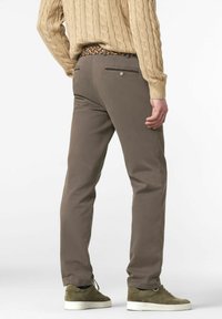 Pantalons en coton marron à jambe droite, avec des poches arrière et une ceinture tissée à motif. Associés à des baskets vert olive.