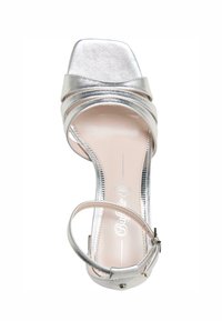 Sandalia de tacón alto plateada con punta cuadrada, tiras cruzadas y una delgada correa para el tobillo. Acabado metálico suave con plantilla beige.