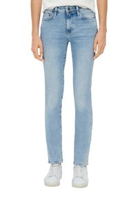 Jean skinny en denim bleu clair avec une taille mi-haute, design à cinq poches et légère décoloration ; accompagné de baskets blanches.