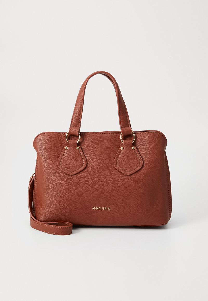 Sac à main texturé marron avec poignées doubles, quincaillerie dorée et une bandoulière amovible. Il présente un logo à l'avant et une forme structurée.