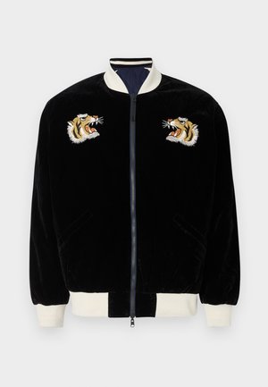 Βελούδινο μπουφάν bomber σε μαύρο χρώμα με λευκό ριμπ κολάρο και μανσέτες. Διαθέτει δύο κεντημένες κεφαλές τίγρης στο στήθος. Περιλαμβάνει πλαϊνές τσέπες.