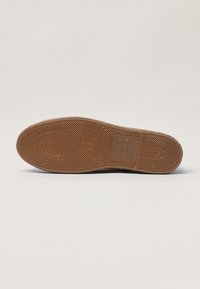 Rubber shoe sole with a textured pattern, featuring a light brown color and visible size marking "42, MADE IN SPAIN," on a white background.