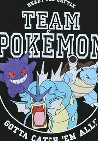 Schwarzes T-Shirt mit Pokémon-Charakteren: Gengar (lila, grinsend), Gyarados (blau, furchtlos) und Blastoise (blau, bewaffnet). Der Text lautet "TEAM POKÉMON."