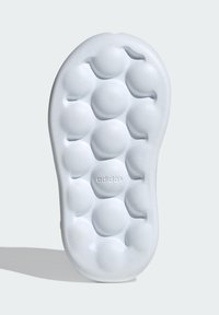 Suela de zapatilla blanca con un patrón texturizado de burbujas circulares elevadas y un pequeño logo de "adidas" cerca del talón.