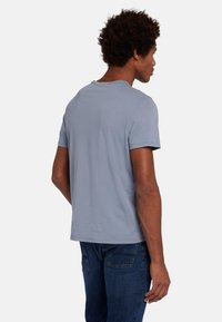 T-shirt di cotone azzurro chiaro con maniche corte, scollatura rotonda e vestibilità morbida. Il tessuto appare morbido e leggermente testurizzato.