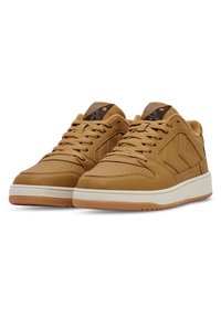 Ett par tanfärgade låga sneakers med snörning, vita mellansulor, gummiyttersulor och vadderad innerfoder, visade mot en vit bakgrund.