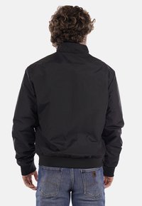 Schwarze Bomberjacke mit glatter, leicht glänzender Textur und gerippten Bündchen. Hat einen hohen Kragen und einen elastischen Saum. Rückansicht gezeigt.