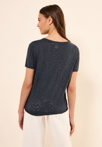 Camiseta de manga corta color azul marino con una sutil textura de estampado animal, que presenta un cuello redondo y un corte relaxed, hecha de una tela ligera.