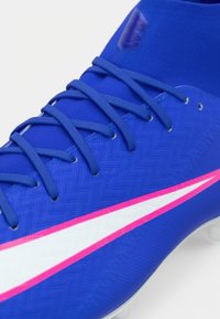 Μπλε ποδοσφαιρικά παπούτσια με υφή στην πάνω επιφάνεια, λευκές και ροζ σχεδιαστικές λεπτομέρειες, και κορδόνια για ασφαλή εφαρμογή. Ελαφριά με αεροδυναμικό σχήμα.
