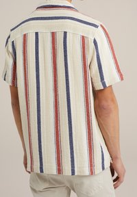 Kortärmad skjorta i ett strukturerat, vävt tyg. Har vertikala ränder i rött, marinblått och krämvitt. Knappkrage och detalj med ryggok.