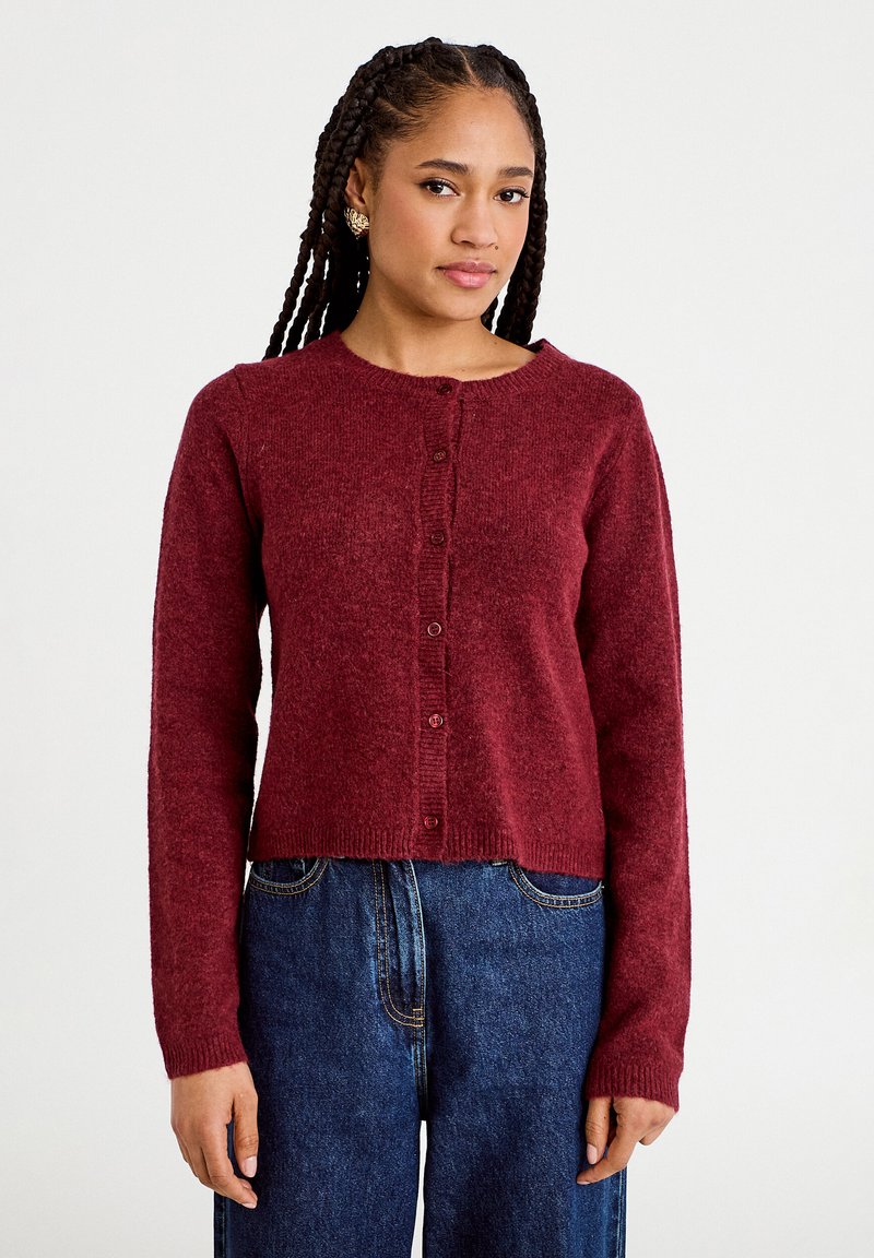 Cárdigan de punto color burdeos con mangas largas, cuello redondo y cierre de botones, que presenta una textura suave y puños y dobladillo acanalados.