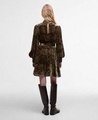 Robe verte à motif floral avec des manches longues, un trou de serrure à l'arrière et une jupe évasée ; assortie à des bottes en cuir marron jusqu'aux genoux.