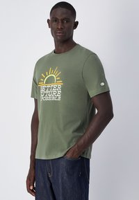 Camiseta de algodón verde oliva con cuello redondo, mangas cortas y un gráfico frontal que dice "UN FUTURO MEJOR ES POSIBLE" con un diseño de sol.