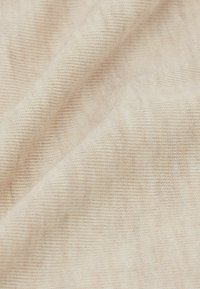 Jasno beżowa tkanina o miękkiej, fakturowanej powierzchni; charakteryzuje się drobnym prążkowanym wzorem, tworzącym subtelną głębię wizualną.