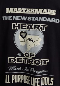 Černé tričko s grafickým designem, na kterém je vytištěn text "MASTERMADE," "HEART OF DETROIT," a obrys mapy, v bílé a šedé barvě.