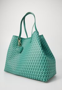Groene draagtas met een gestructureerd patroon, voorzien van twee handvatten en een hartvormige hanger. Gemaakt van synthetische materialen.