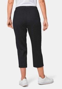 Navy cropped broek gemaakt van gestructureerde stof met een elastische tailleband, gedragen met witte sneakers.