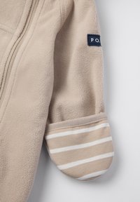 Beige fleeceærme med en lynlåseam og en manchet med beige og hvide vandrette striber samt en lille marineblå lap med teksten "P.O.".